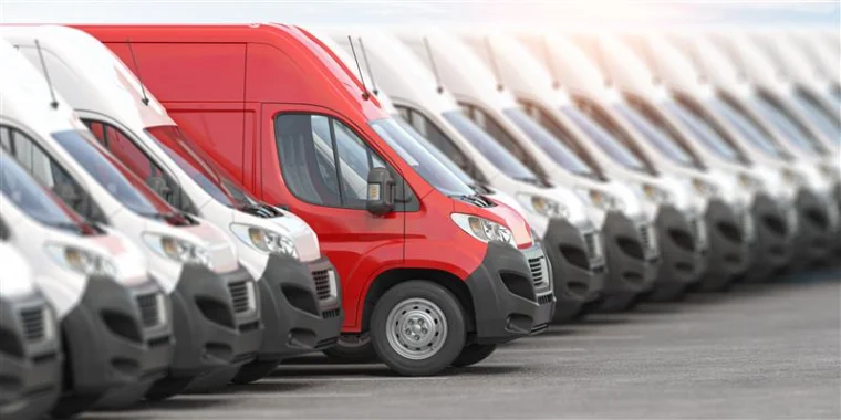 Red delivery van among a line of white vans.