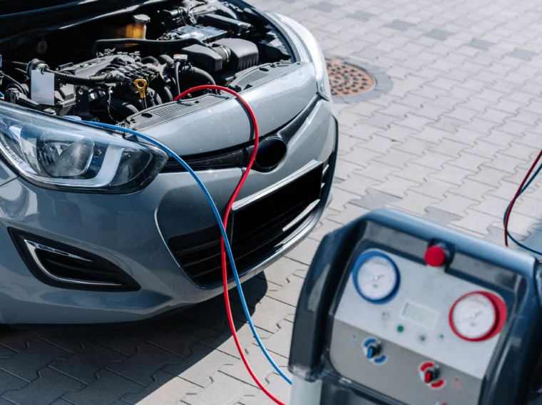 A vehicle with it hood up showing two hoses coming out of it that are hooked up to a diagnostic machine.