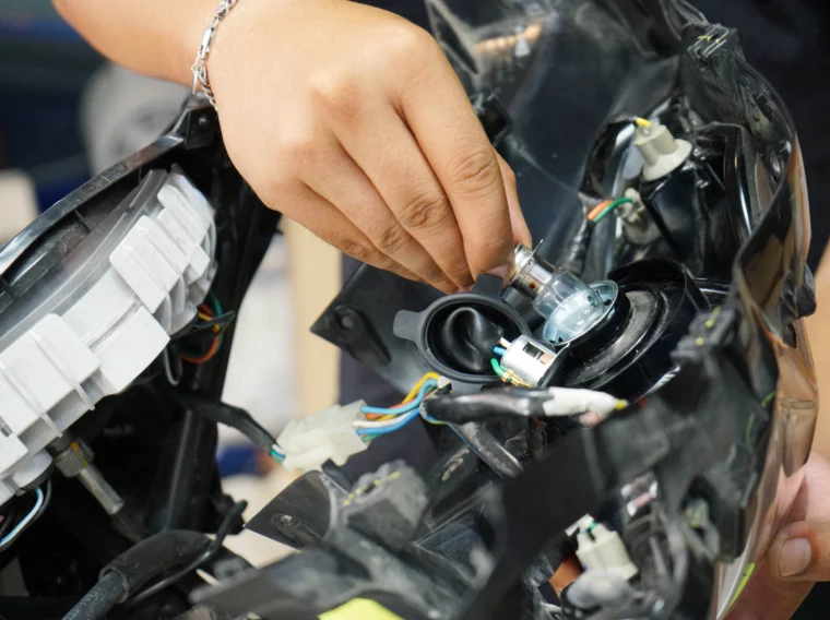 A hand replacing the light bulb of a vehicle.